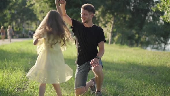 Carefree Playful Girl Spinning in Sunshine Holding Man Hand