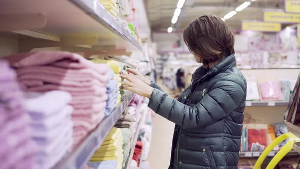 Beautiful Woman in Coat Inspecting and Buying Towels in Supermarket