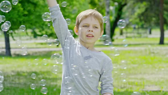 Happy Boy Making Giant Soap Bubble in Park alt