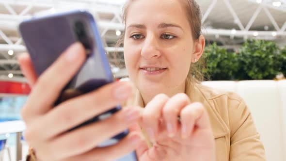 Closeup Video of Smiling Young Woman Typing Message in Social Media on Smartphone While Sitting in