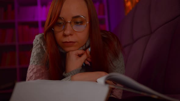 A Beautiful Student with Glasses Reading a Big Book