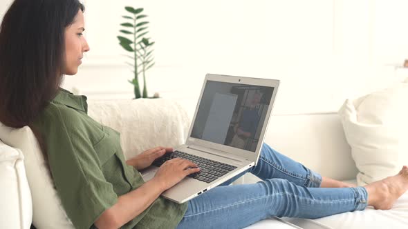 Indian Woman Studying By Video Lying Down on the Couch with Laptop