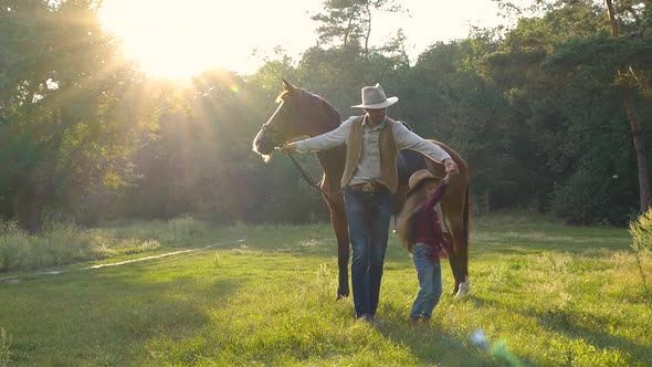 A Cowboy with a Horse and His Beautiful Daughter are Walking in the Pasture