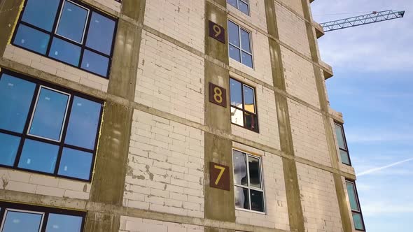 Aerial view of high residential apartment building with storey numbers on wall under construction.