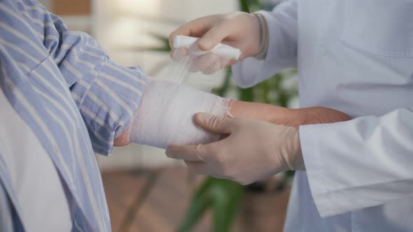 A Physical Therapist Applies a Bandage to a Patient'S Injured Arm