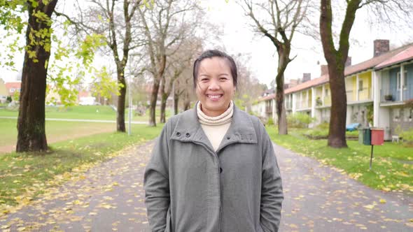 Front view of Asian woman standing and smiling at park