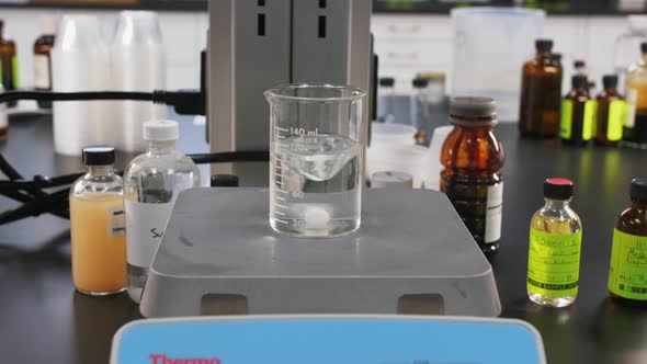 Establishing shot of machine in a science lab testing chemicals in a clear glass bottle.