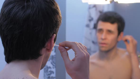 A Man Cleans His Ears in the Bathroom