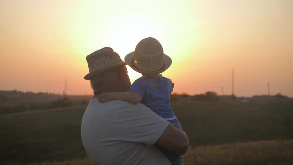 Two Generations Silhouette of a Mature Grandfather and Little Grandson Play at Sunset.