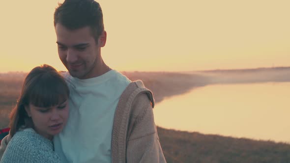 Happy Couple Hugs in Tourist Camp on River Bank at Sunset