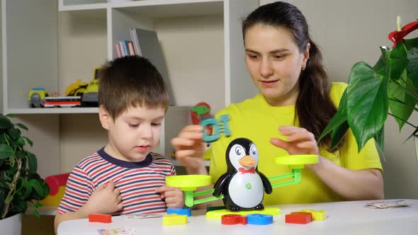 Mom and Son Play with Numbers Weigh a Penguin on a Toy Scale