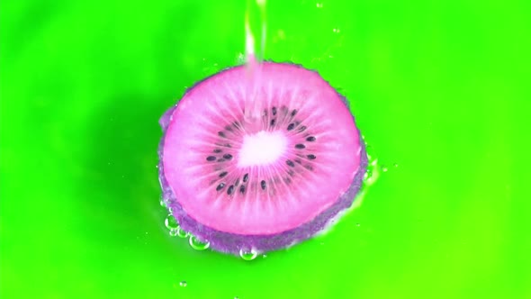 Water pours on purple hue juicy kiwi fruit on green background slow motion closeup. Kiwi fruit