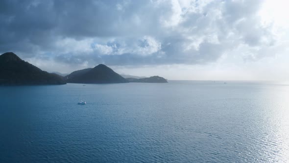 Aerial shot of a white yacht and dark mountains in a calm sea (Rodney Bay, Saint Lucia)