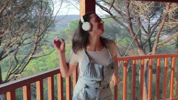 Happy Hispanic Female with Headphones Dancing Alone in His Home Terrace