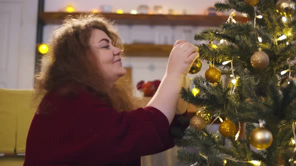 Happy Young Woman Decorating Christmas Tree at Home