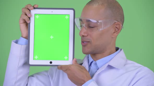 Face of Happy Bald Multi Ethnic Man Doctor with Protective Eyeglasses Showing Digital Tablet