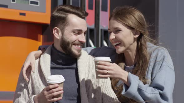 Loving Woman Bringing Coffee to Boyfriend at Gas Station