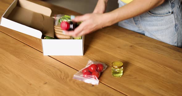 Woman open a delivery box meal kit and pulls fresh ingredients