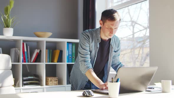 Young male entrepreneur works at home office at the computer.