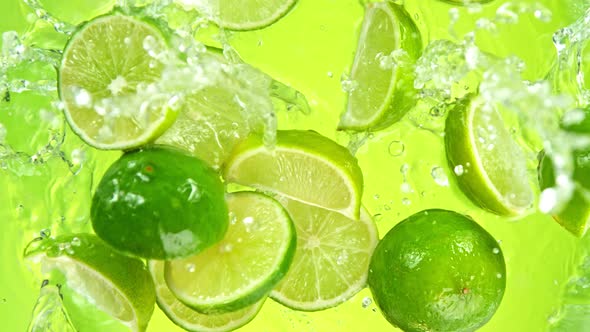 Super Slow Motion Shot of Lime Slices Falling Into Water on Green Background at 1000Fps