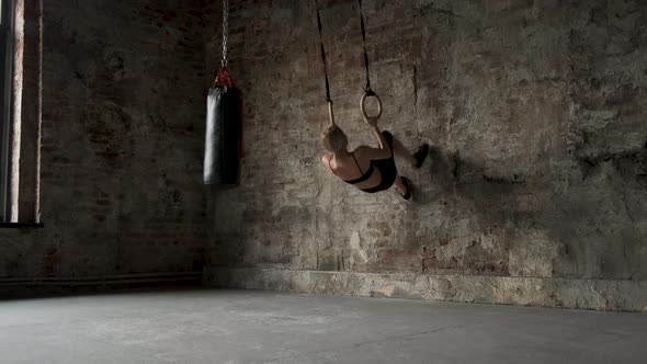 Sporty girl doing flips on sports rings. Young fit woman doing stretching on gymnastic rings. 