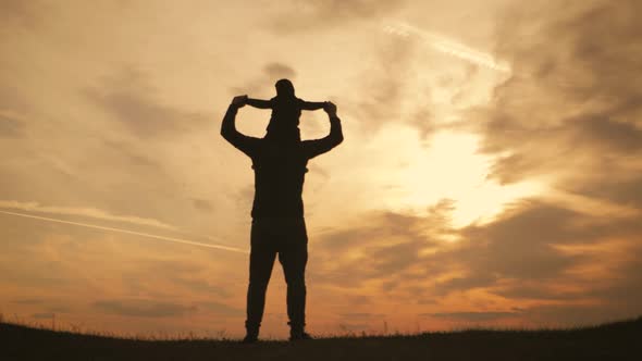 Silhouettes Father and Little Son Playing on the Meadow at the Sunset Time. Concept of Friendly