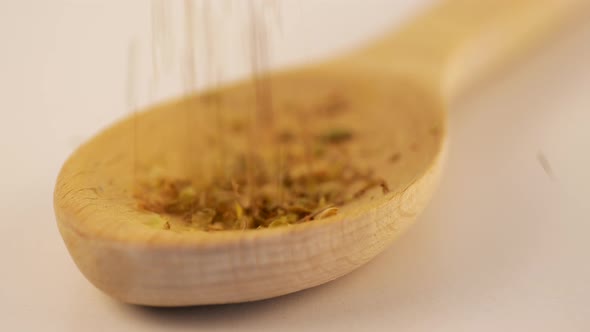 Dry Oregano Strewed From Above Into a Wooden Scoop