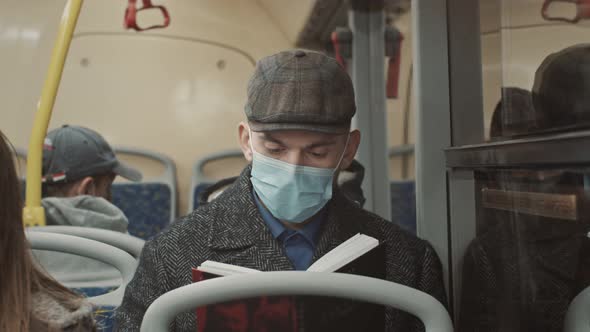 Young Handsome Man Sitting on Public Transport Reading a Book