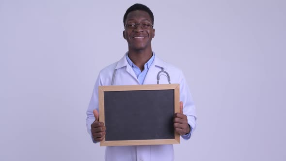 Young Happy African Man Doctor Holding Blackboard