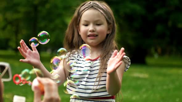 A 6Yearold Girl Happily Catches Rainbow Bubbles That Her Mother Blows