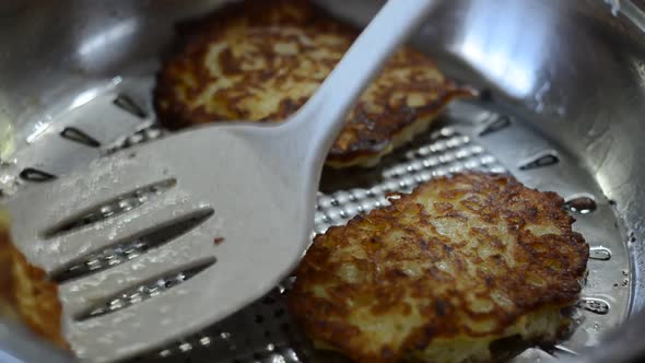 The cook fries zucchini pancakes in a pan