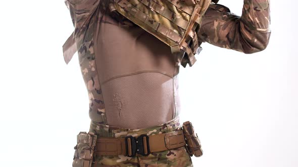 Military specialist in a tactical outfit puts an armor plate carrier on his body