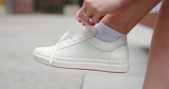 Unrecognizable Woman Tie Shoelaces on White Sneakers