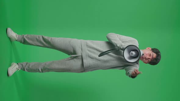 Full Body Of Asian Man Speaking On Megaphone In The Green Screen Studio