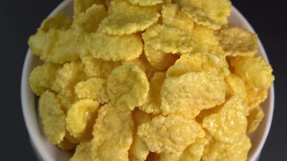 Crispy corn flakes rotating in bowl close up, dry healthy breakfast. Honey cornflakes for healthy