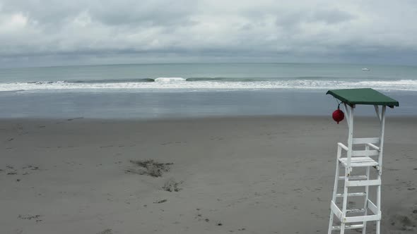 Zooming in on a deserted beach with small waves alongside a lifeguard post