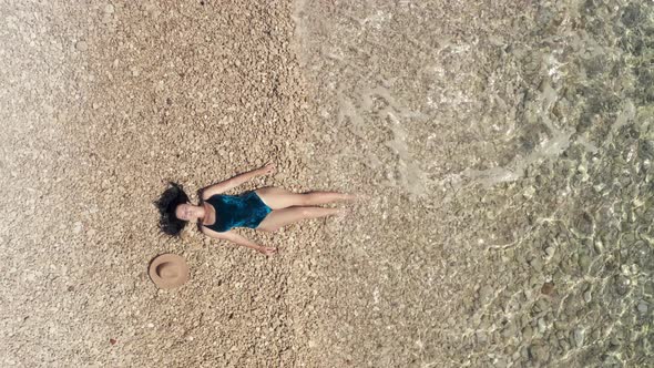 Aerial View Girl in a Bathing Suit Sunbathes By the Sea