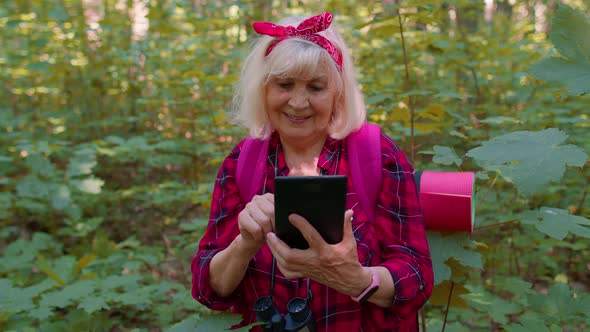 Active Elderly Senior Grandmother Adventurer Exploring Forest Trees Plants with Her Digital Tablet