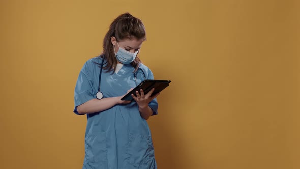 Portrait of Woman Doctor Holding Tablet Typing Patient Data Wearing Hospital Uniform and Covid