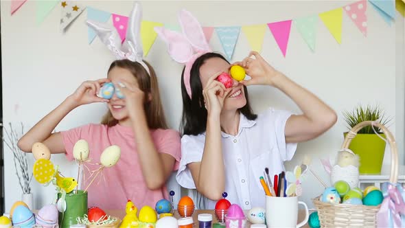 Mother and Her Little Daughter Painting Eggs. Happy Family Preparing for Easter