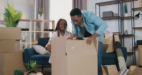 Couple Having Fun Together with Their Two Cute Small Daughters which Hiding in Cardboard Packing