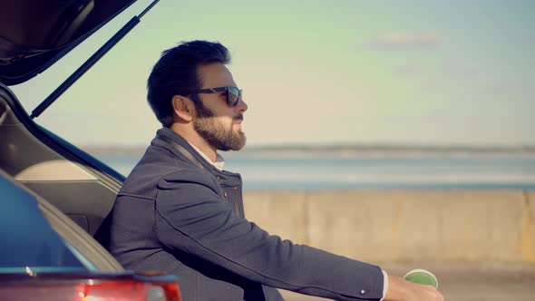 Man Resting On City Beach. Cheerful Romantic Guy In Sunglasses Walks On Sand And Dreaming.