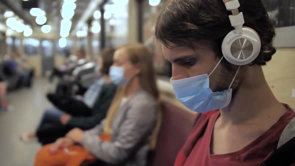 Man in Face Mask and Headphones in Metro Train