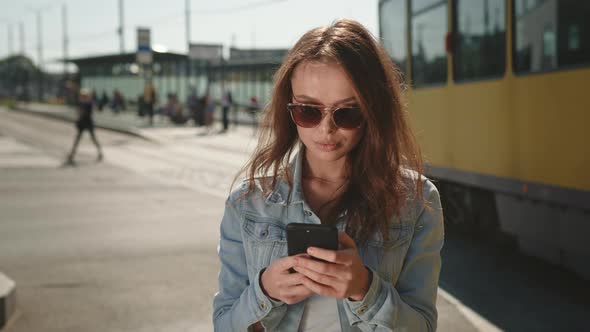 A Young Woman is Standing at the Train Station