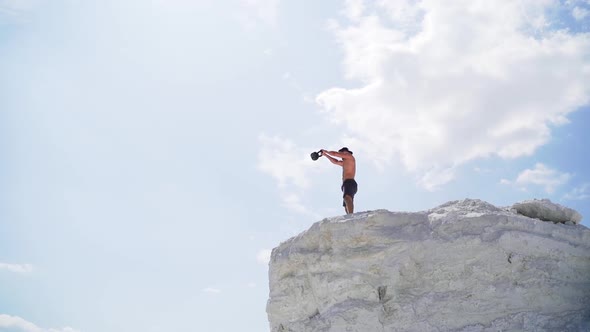 View from below on a healthy man training with heavy weight on a hill