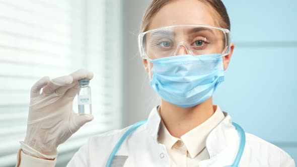 Young woman researcher in blue disposable mask glasses