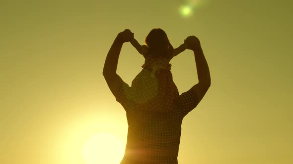 Dad Carries Beloved Baby on His Shoulders Walking Around Field at Sunset,  Little Daughter Riding