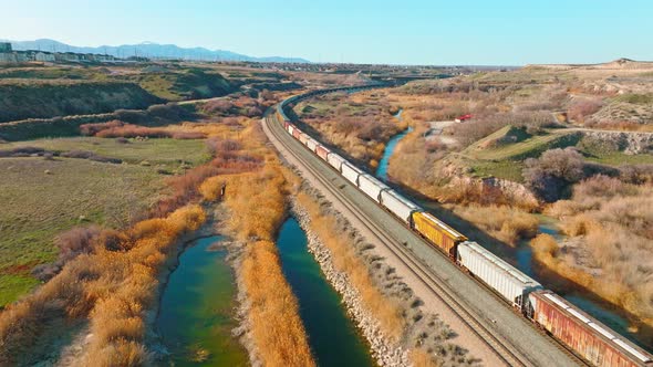 AERIAL - Train on railroad tracks close to Bluffdale, Utah, forward lowering shot