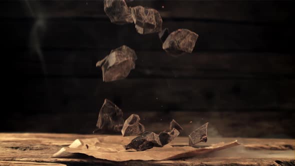 Super Slow Motion Falling Pieces of Bitter Dark Chocolate on a Wooden Table