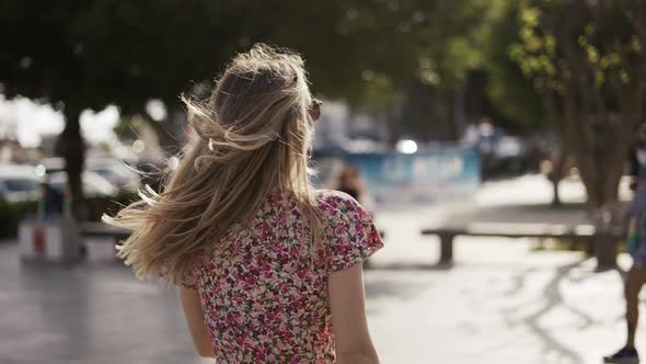 Camera Follows Young Blondy Woman in Dress in Sunny Summer Day